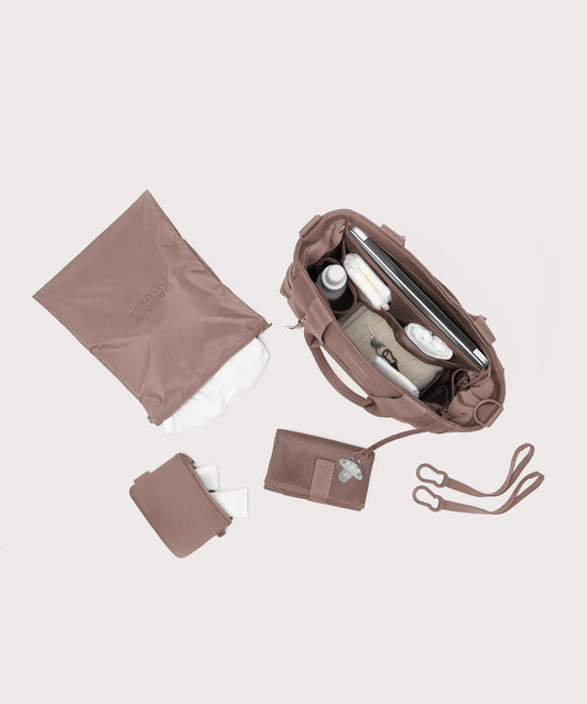 Dagne Dover large Wade Diaper Tote in pink seen from above, alongside the changing mat, neoprene pouch, and water resistant zipper bag.